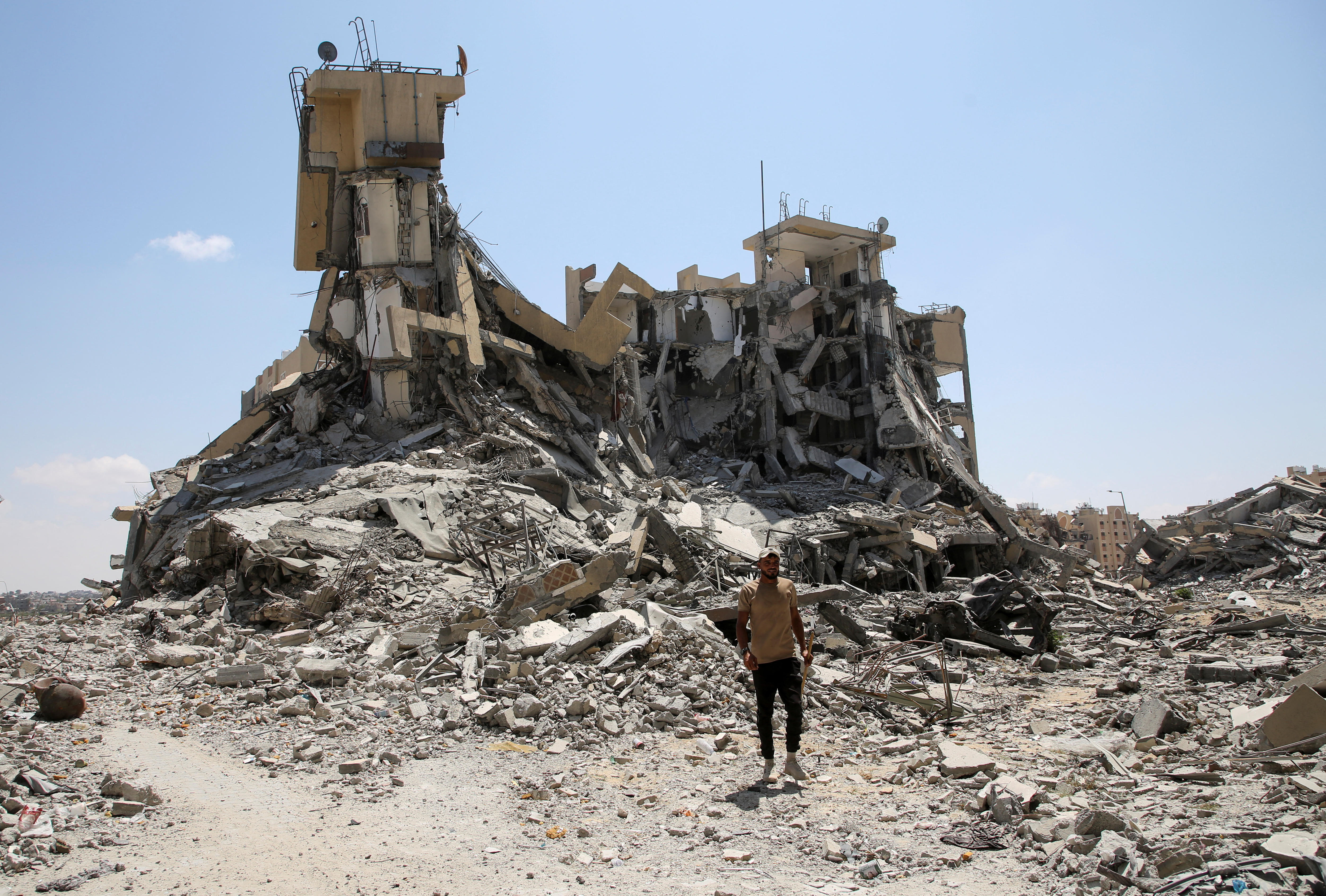 A man stands in front of a torn down residential building