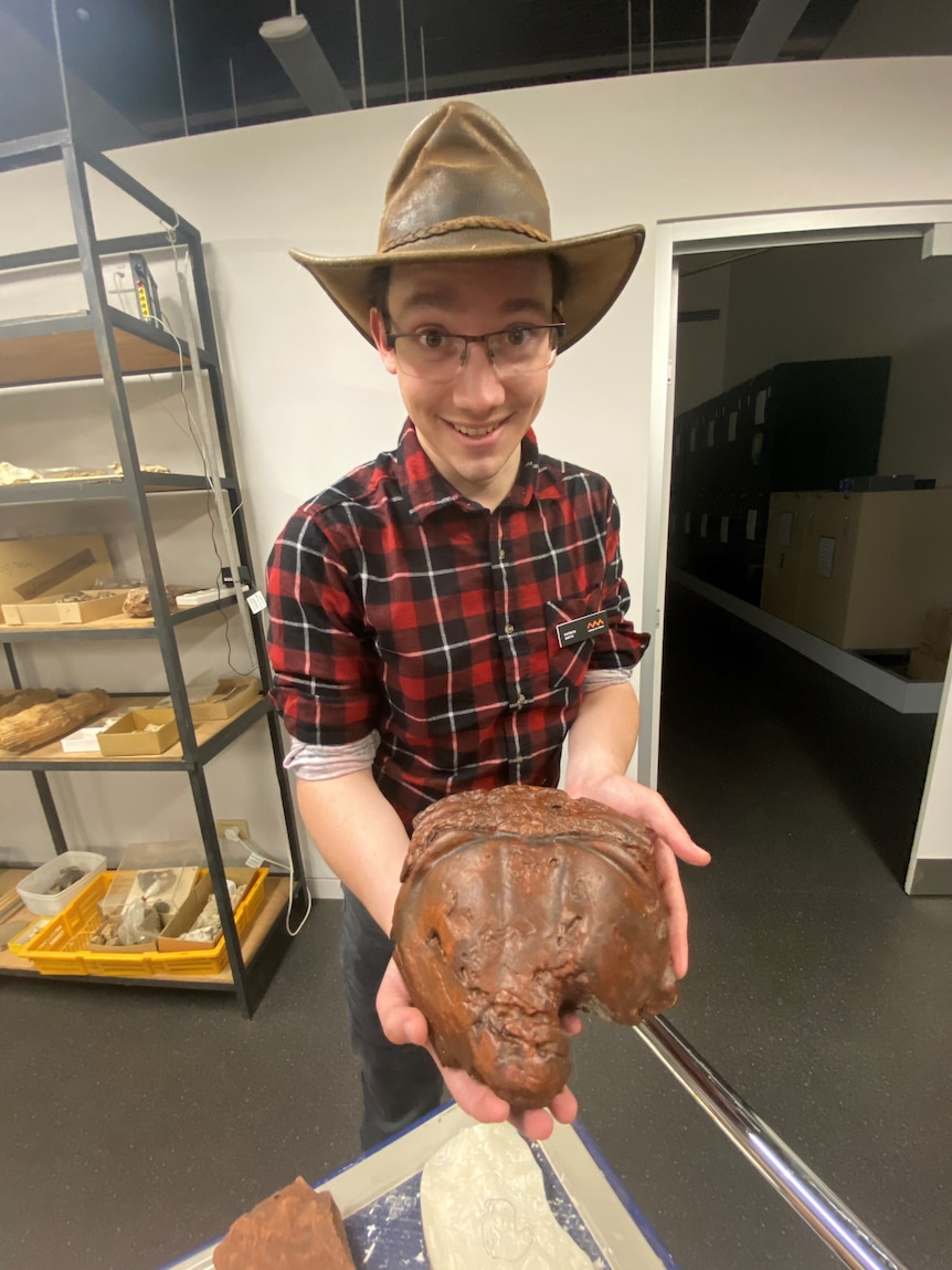A man holding a 3D replica of a trilobite's tail