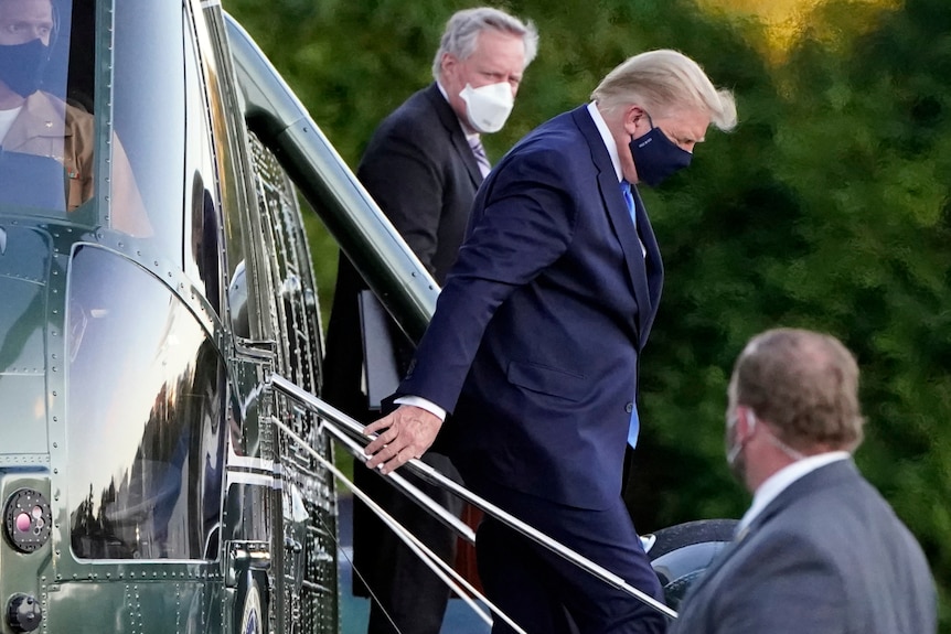 US President Donald Trump wearing a face mask, walking down the stairs of Marine One.