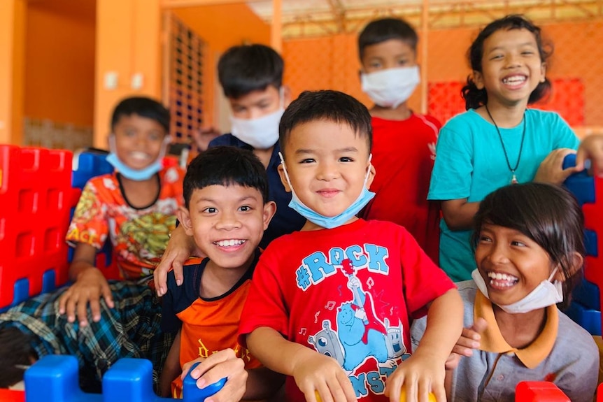 Seven children smiling some wearing masks