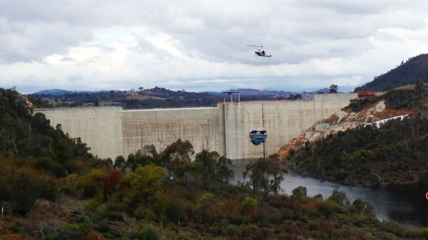 A helicopter places one of the turbines into Cotter Dam.