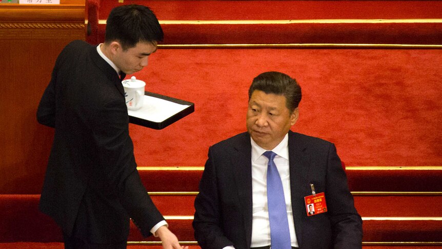 Chinese President Xi Jinping watches as an attendant delivers a cup of tea at the opening of parliament.