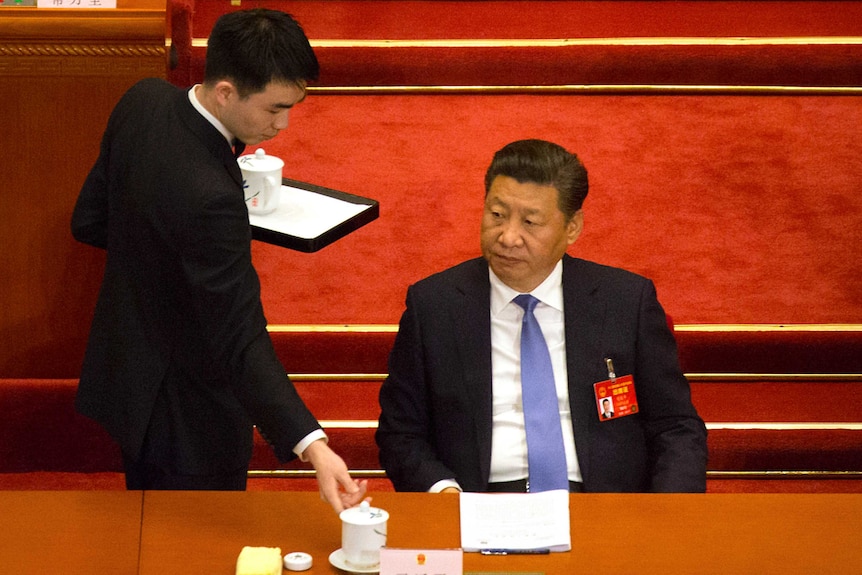 Chinese President Xi Jinping watches as an attendant delivers a cup of tea at the opening of parliament.