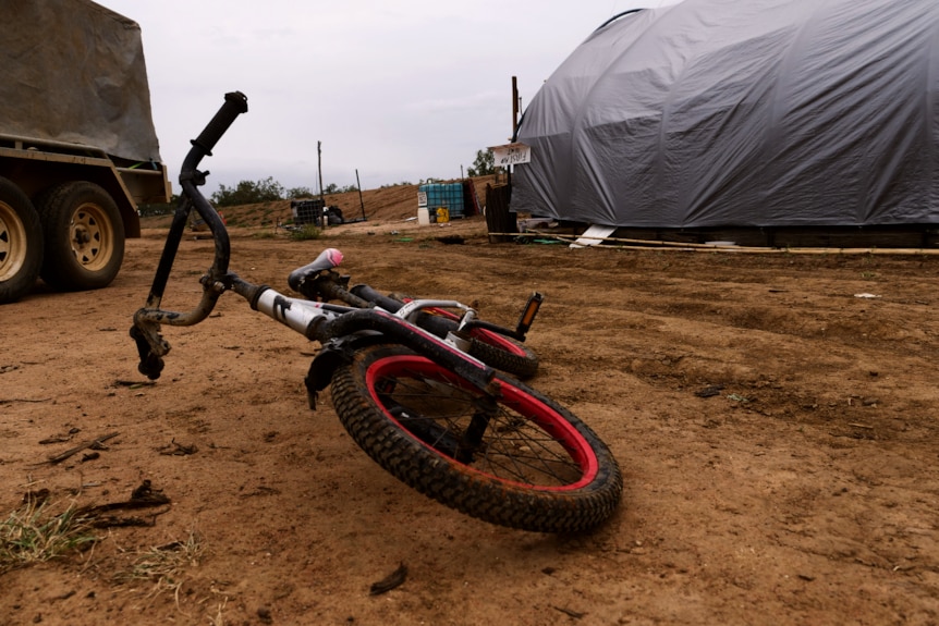 a red and black bike lies on its side on the dirt