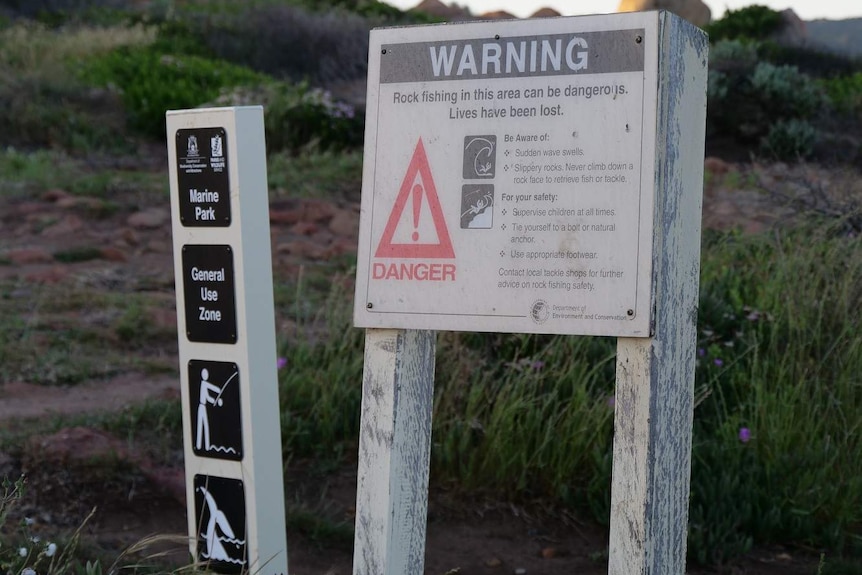 Two signs which show the warning labels for rock fishers near rocks.