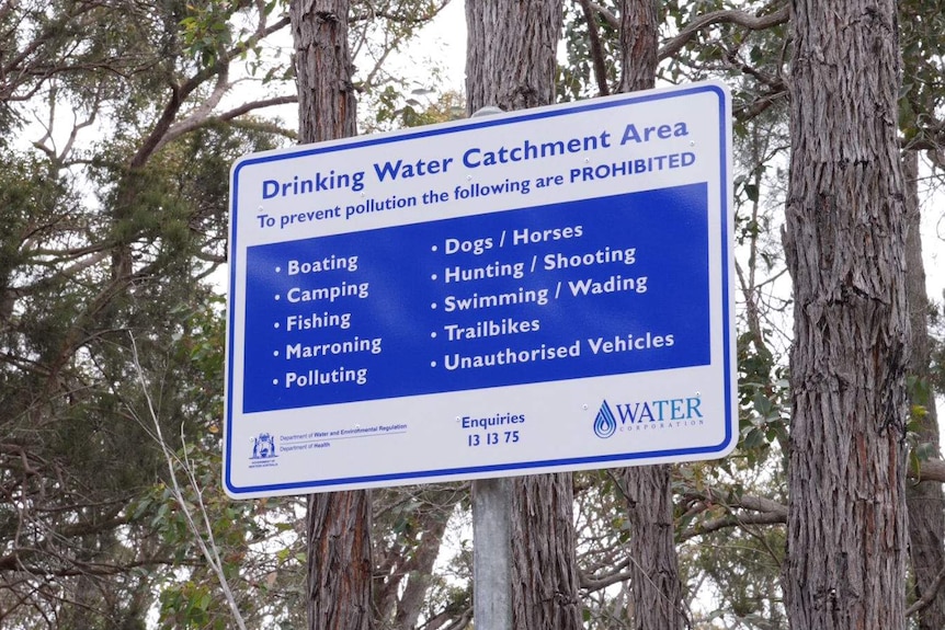 A blue and white sign near trees that says 'Drinking Water Catchment Area'.