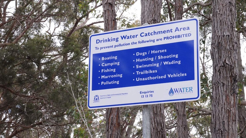 A blue and white sign near trees that says 'Drinking Water Catchment Area'.