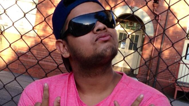 A man in sunglasses and a pink t-shirt posing for a photo