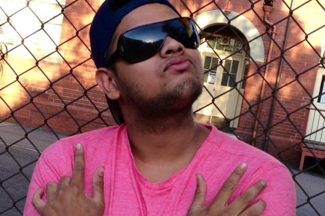 A man in sunglasses and a pink t-shirt posing for a photo