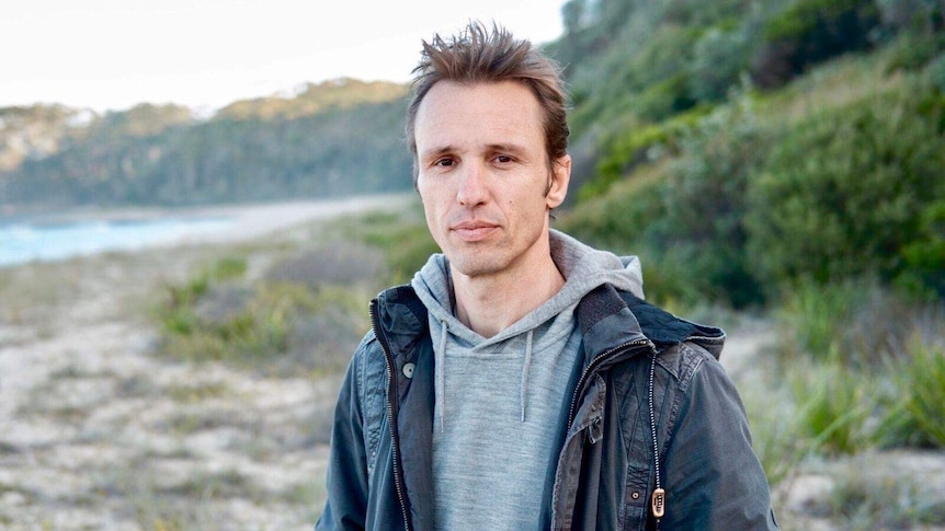 A man stands in front of a beach