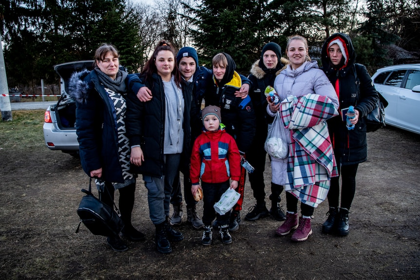 A group of people stand together in a car park 