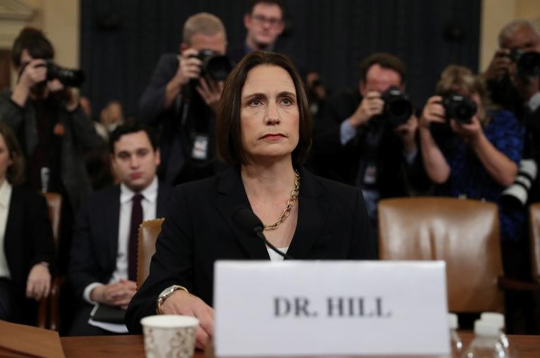 Fiona Hill, former senior director for Europe and Russia on the National Security Council sitting down, photographers behind her