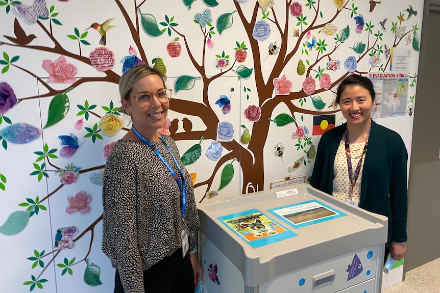 two woman are pictured next to a tree poster