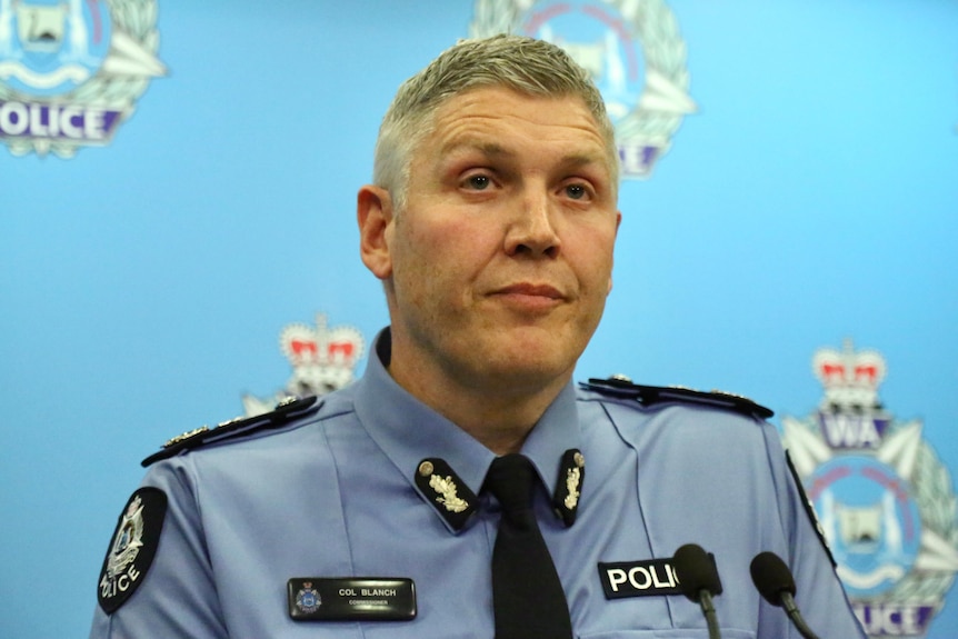 A man in a police uniform looks tired while talking to the media. 