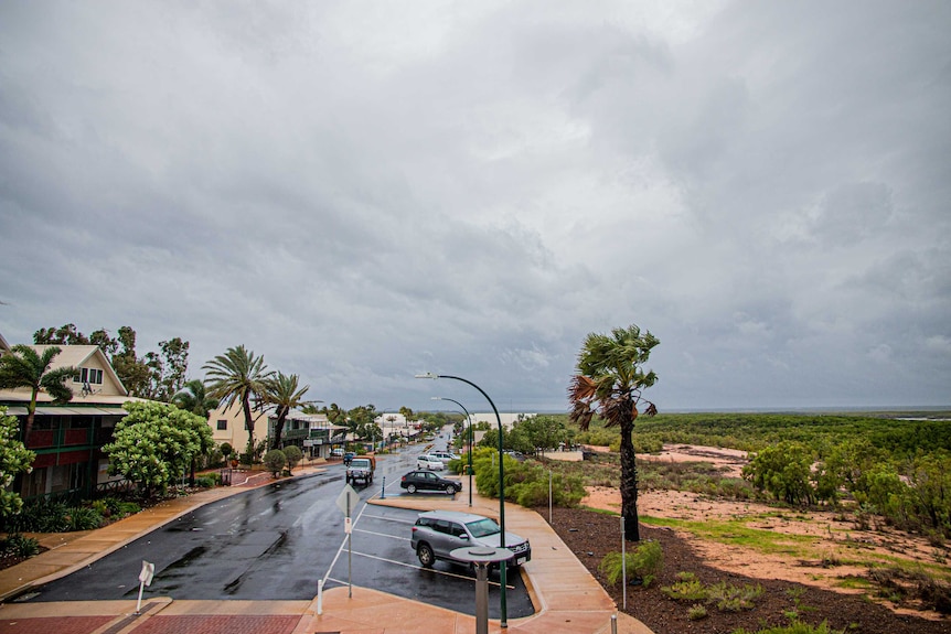 View of wet street in Broome with palm trees blowing in the wind
