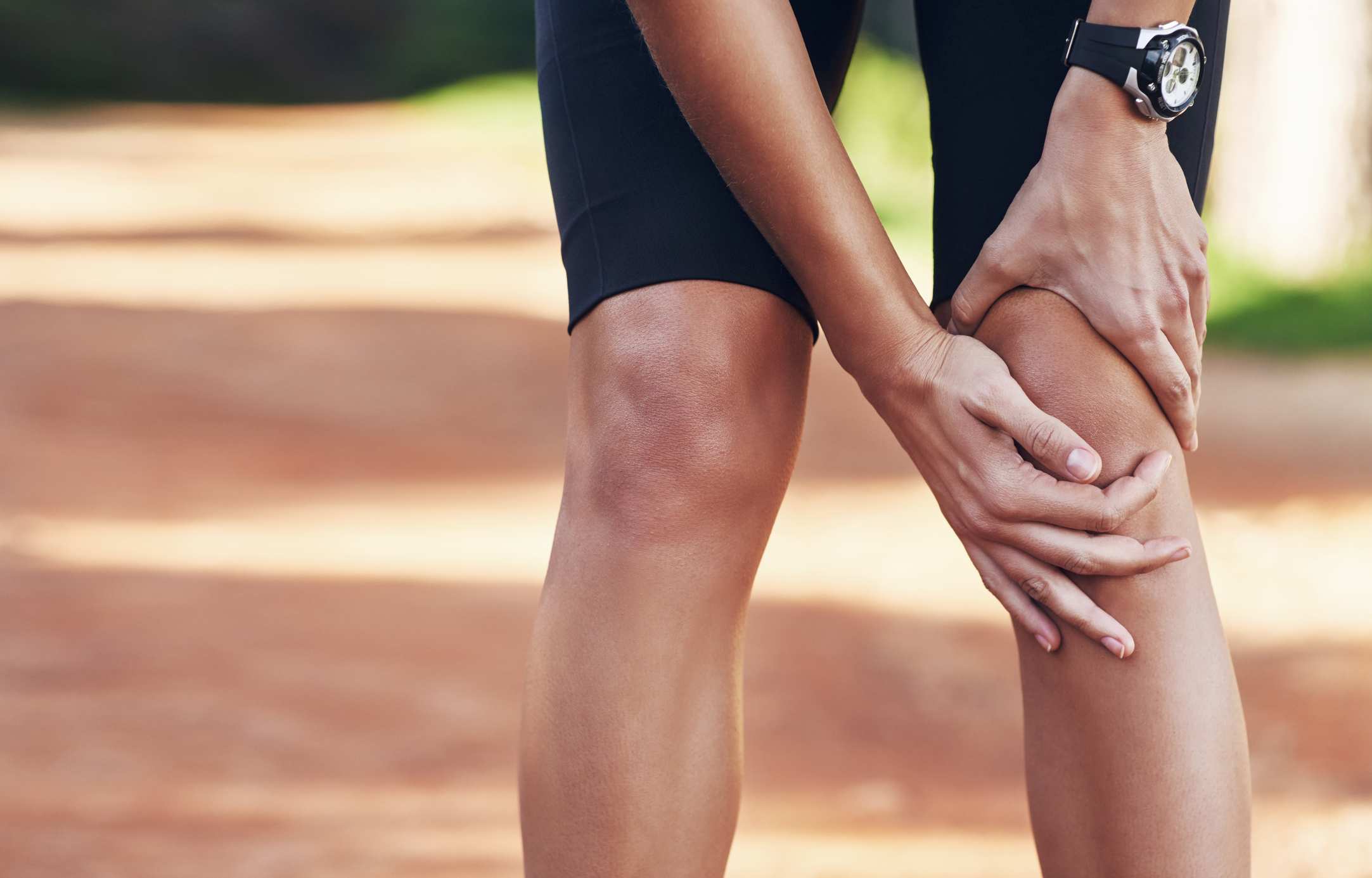 A close-up of a woman holding her knee while doing some form of exercise