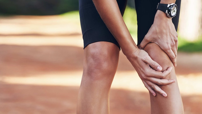 A close-up of a woman holding her knee while doing some form of exercise