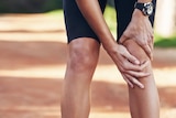 A close-up of a woman holding her knee while doing some form of exercise