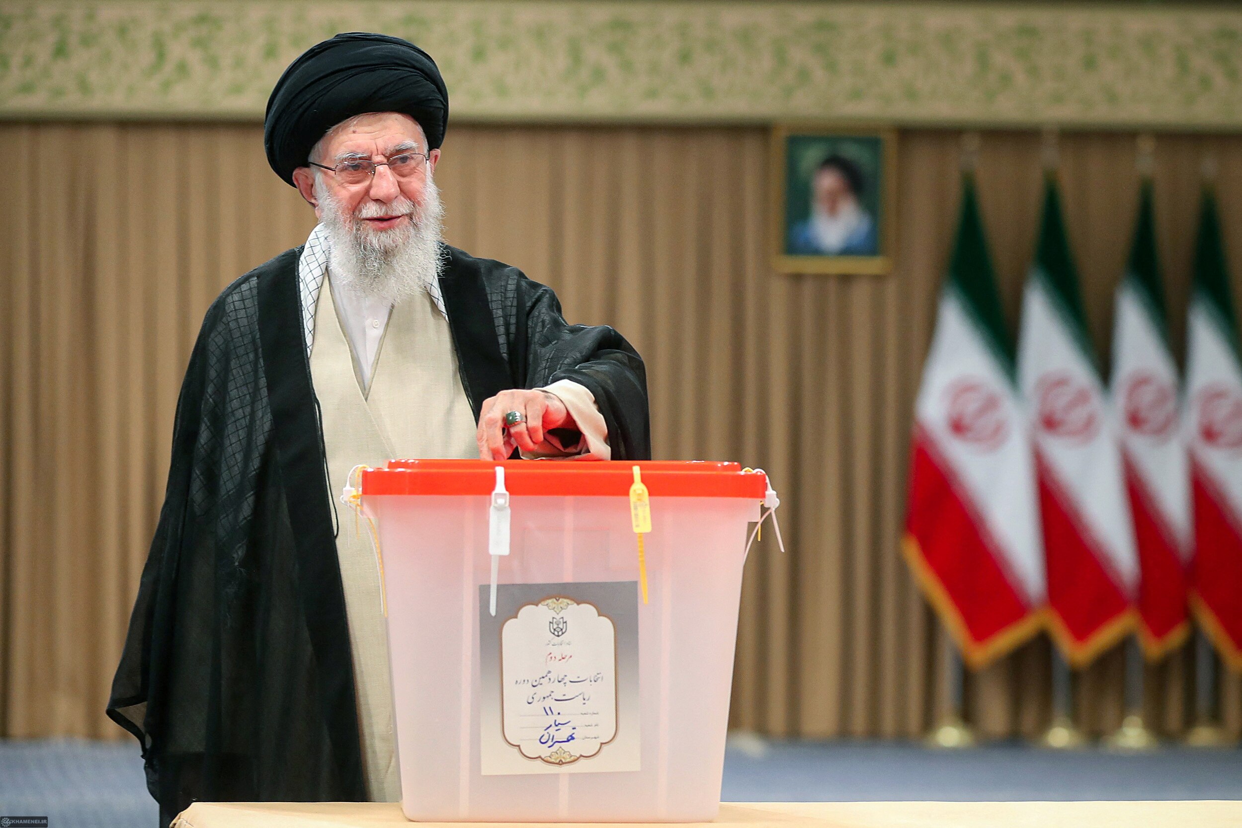 A man wearing a black turban puts an electoral vote into a large box.