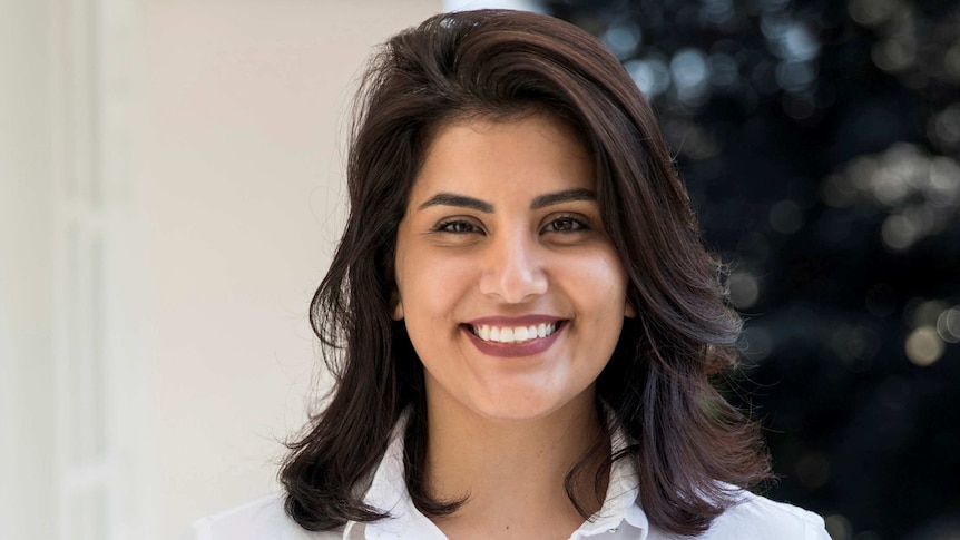 Dark-haired woman in white shirt smiles for camera