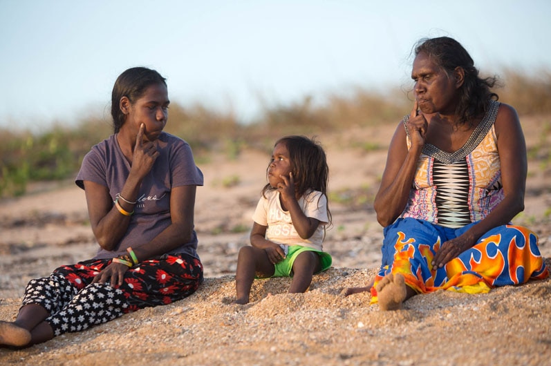 Three generations of Yolngu ladies all doing different sign language movements.