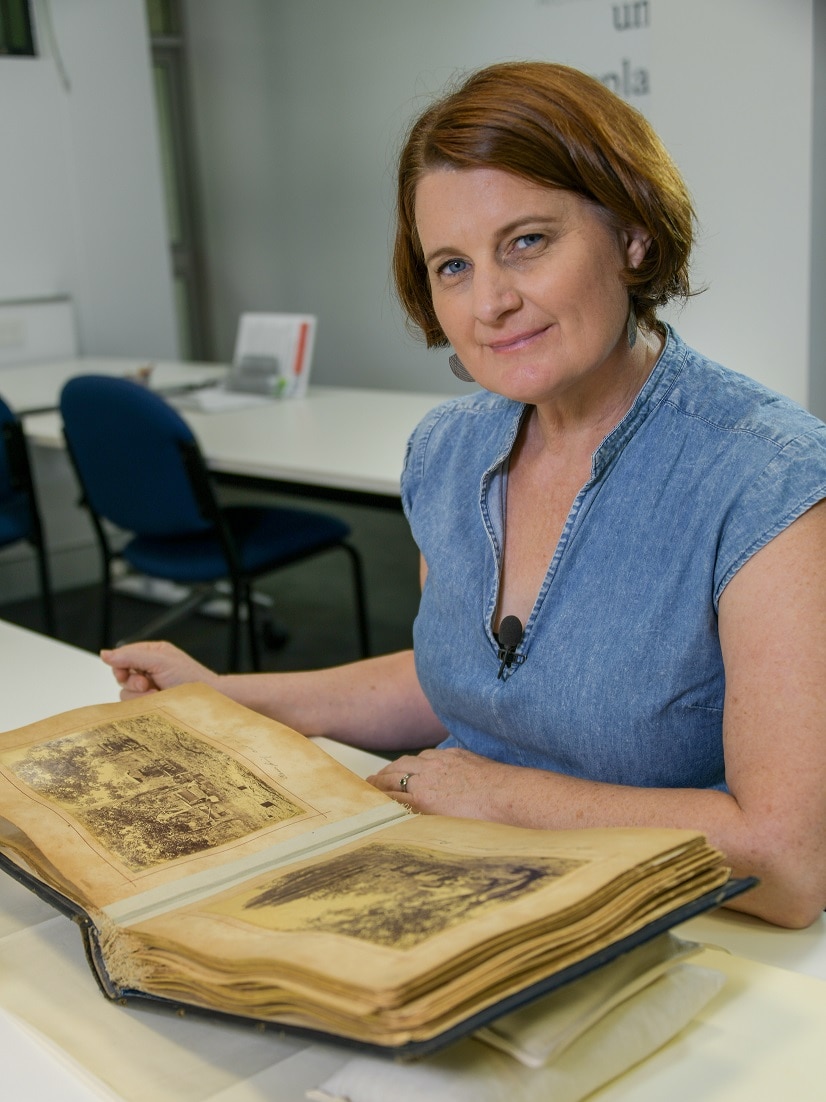 A woman sits by a book