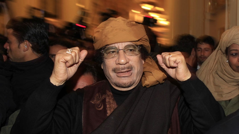 Libya's leader Moamar Gaddafi pumps his fists as he arrives at a hotel to meet the media in Tripoli.