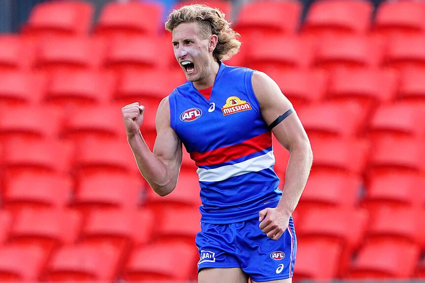 A Western Bulldogs AFL player pumps his right fist as he celebrates a goal against the Adelaide Crows.