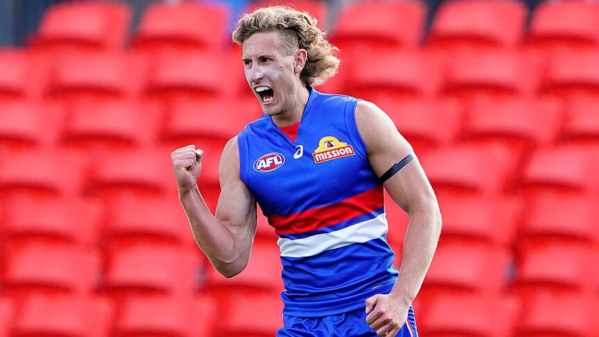 A Western Bulldogs AFL player pumps his right fist as he celebrates a goal against the Adelaide Crows.
