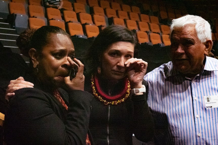two women, and a man wiping away tears, standing in Queensland parliament