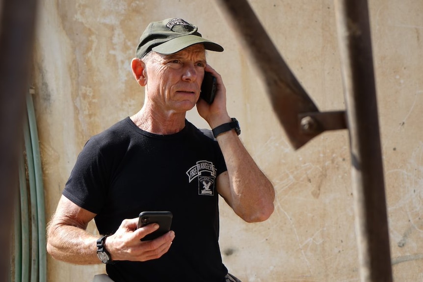 A man speaks on the phone wearing a t-shirt that says Free Burma Rangers.