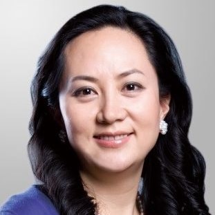 A woman wearing a blue top and a string of pearls smiles into the camera