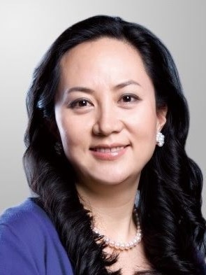 A woman wearing a blue top and a string of pearls smiles into the camera