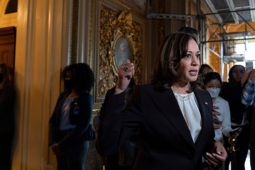 Woman gestures to room behind her while talking to reporters.