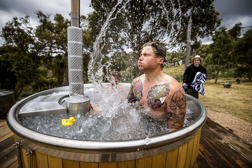 A man holds his breath and flicks his hair in an ice bath