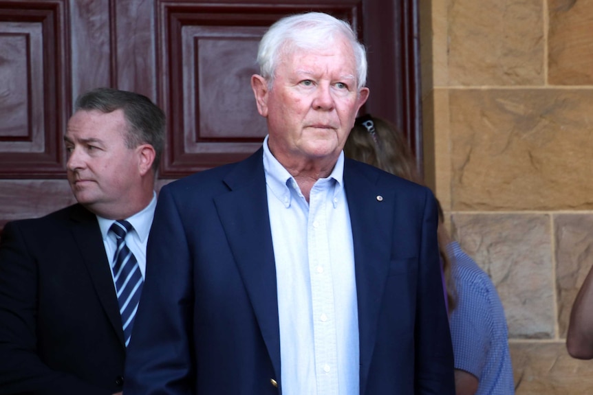 Denis walks out of the court, looking sombre.