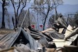 Burnt remains of a house destroyed in a bushfire, with child's swing seat in background, at Kabra, near Gracemere.