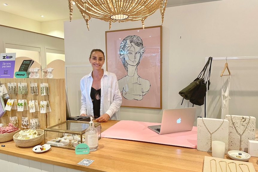 A smartly dressed woman in a shop painted in alluring pastel colours.