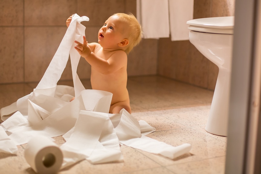 A baby tangled in toilet paper roll.