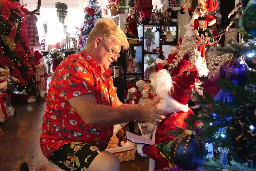 A man in a Christmas shop examining ornaments