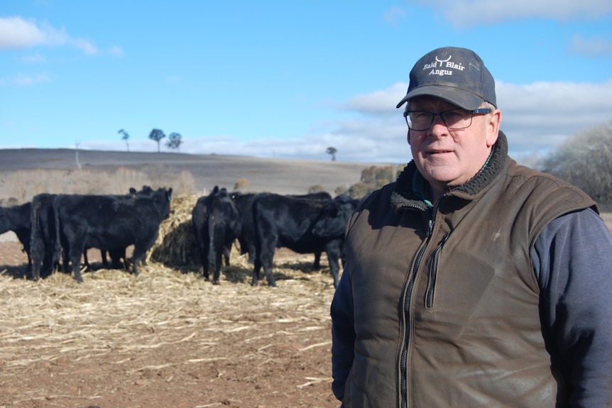 man grimaces to camera in front of brown fields