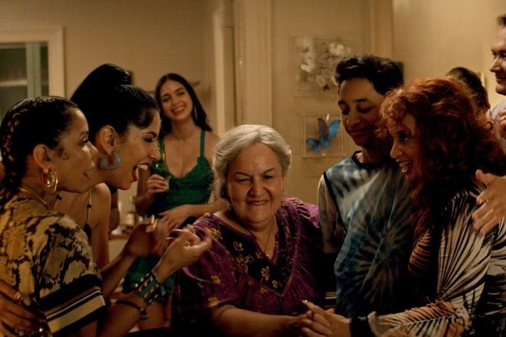 A group of people embracing an older woman with excitement.