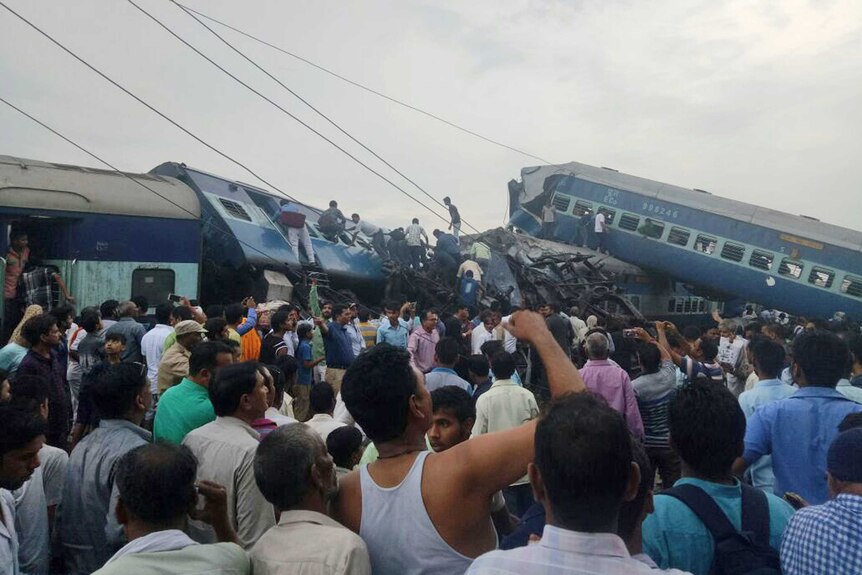 Railway police and local volunteers look for survivors on top of mangled train carriages.