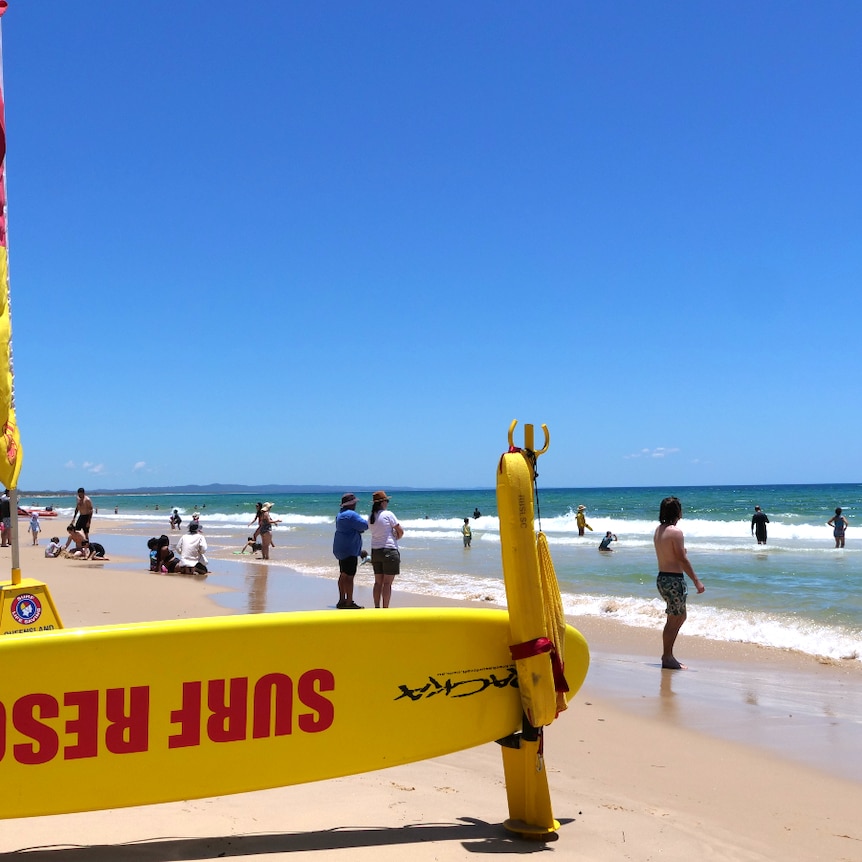 a busy beach with a surf rescue board