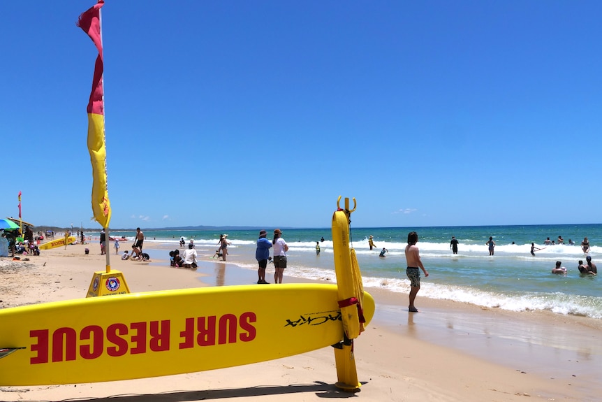 a busy beach with a surf rescue board