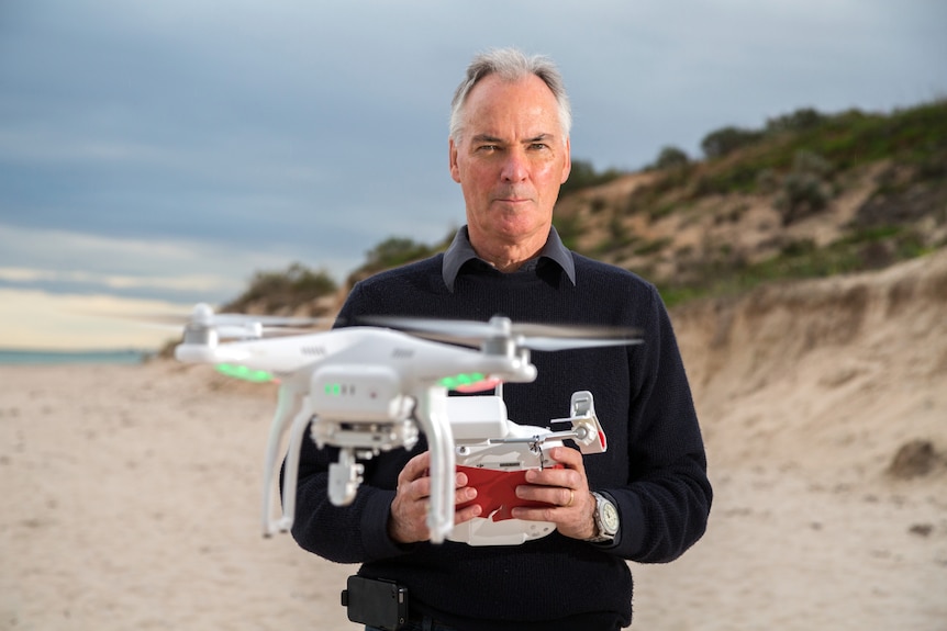 A man with grey hair pilots a drone.