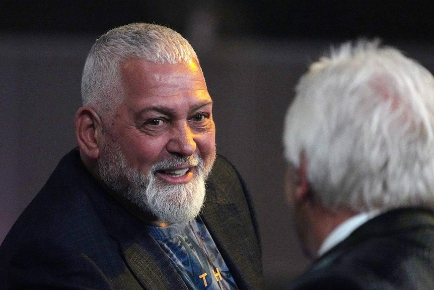 Mick Gatto smiles while chatting to another man