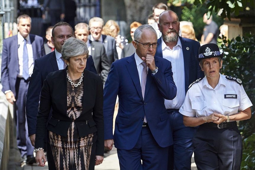 Theresa May and Malcolm Turnbull look solemn as they walk with the Met Police Commissioner during a visit to Borough Market.