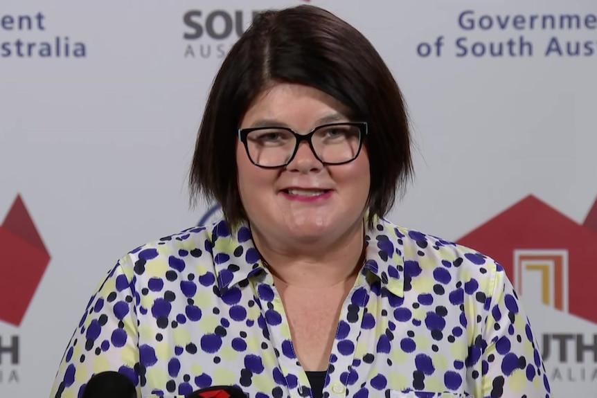 A woman with dark brown hair wearing glasses and a black and white spotty shirt