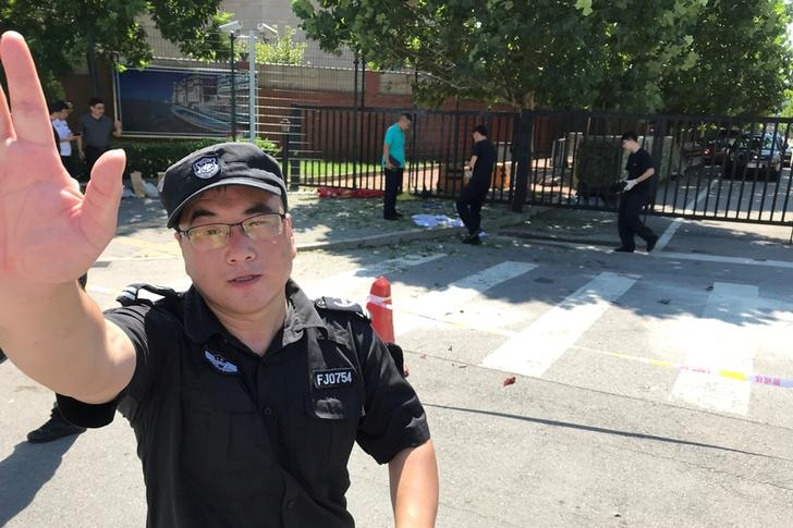 Security person raises hand to camera outside US Embassy in Beijing